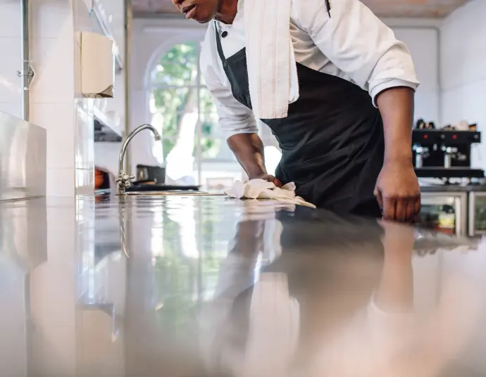 Powerful Performance: Biotech cleaning for deep cleaning, odour control, and proven results. Professional cleaning a stainless steel countertop in a commercial kitchen, showcasing the effectiveness of biotech cleaning solutions