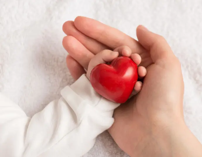 Safer for People: Cleaning solutions that prioritize safety and well-being Adult hand holding a child's hand with a red heart, symbolizing the safety and care provided by InnuScience cleaning solutions.