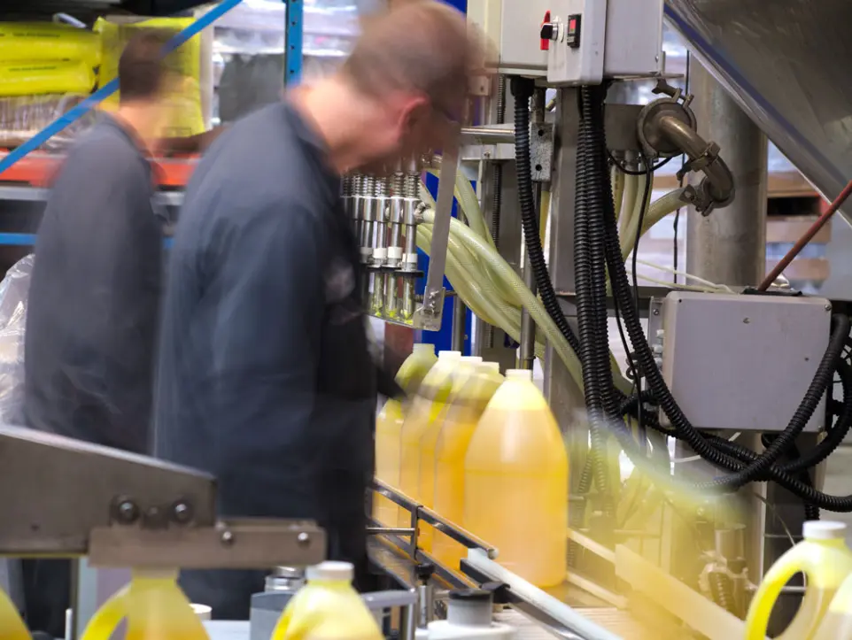 Manufacturing Excellence: Precision, sustainability, and quality in biotech cleaning solutions Workers in a manufacturing facility filling containers with biotech cleaning solutions, showcasing InnuScience's precision and sustainability in production.